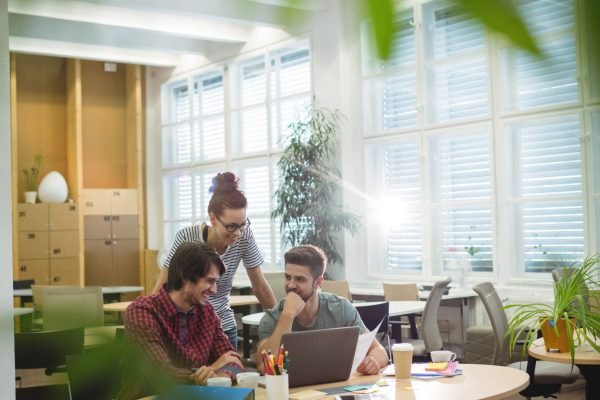 Group of business executives discussing over laptop at their desk in the office